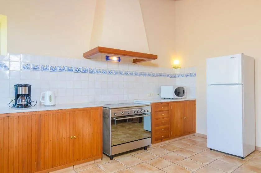 A kitchen with wooden cabinets, a stove, and a refrigerator.