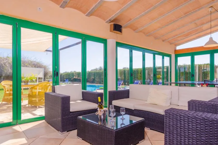A bright sunroom with seating beside large glass doors overlooking a patio.