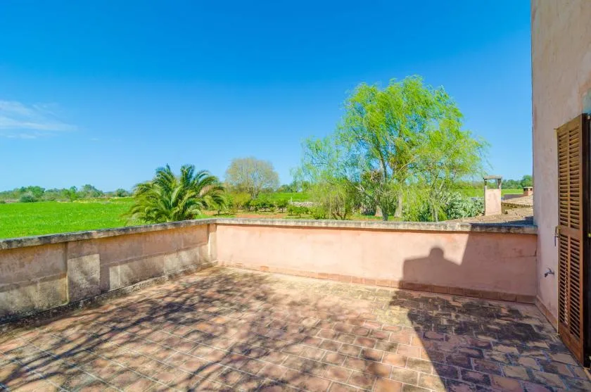 A tiled outdoor terrace overlooks green fields and leafy trees.