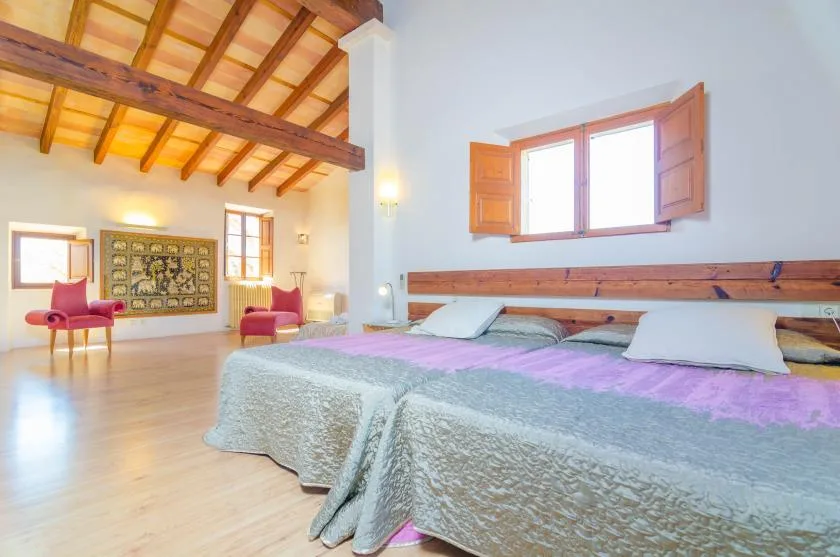 A bedroom with a large bed beneath an open wooden window.