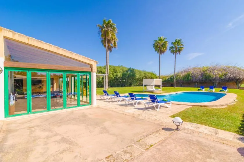 A swimming pool beside a modern building, with lounge seating on the surrounding patio.