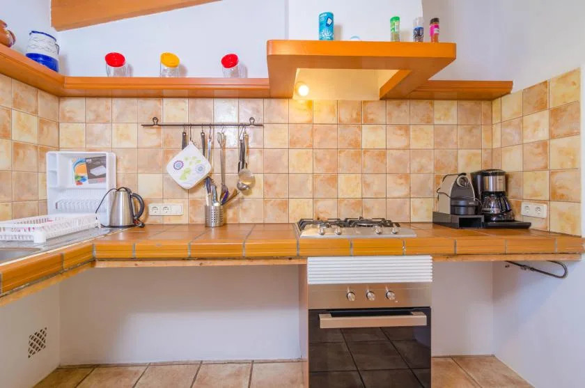 A kitchen with a countertop stove, oven, and small appliances.