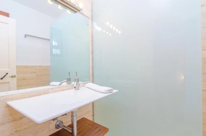 A bathroom vanity with a white basin and a large frosted glass panel.