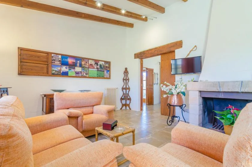 A living room with peach-colored seating, exposed ceiling beams, and a fireplace.