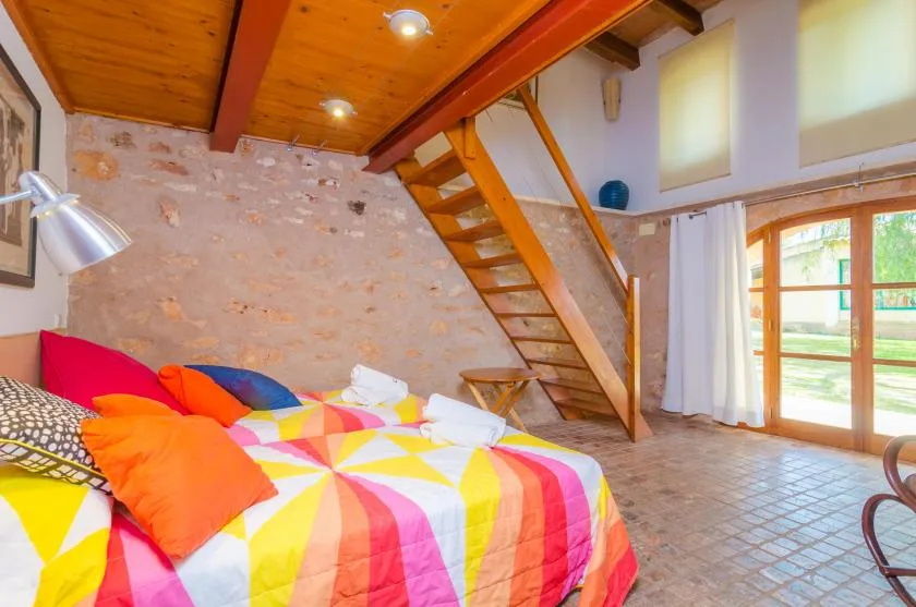 A bedroom with colorful bedding and a wooden staircase leading to a loft.