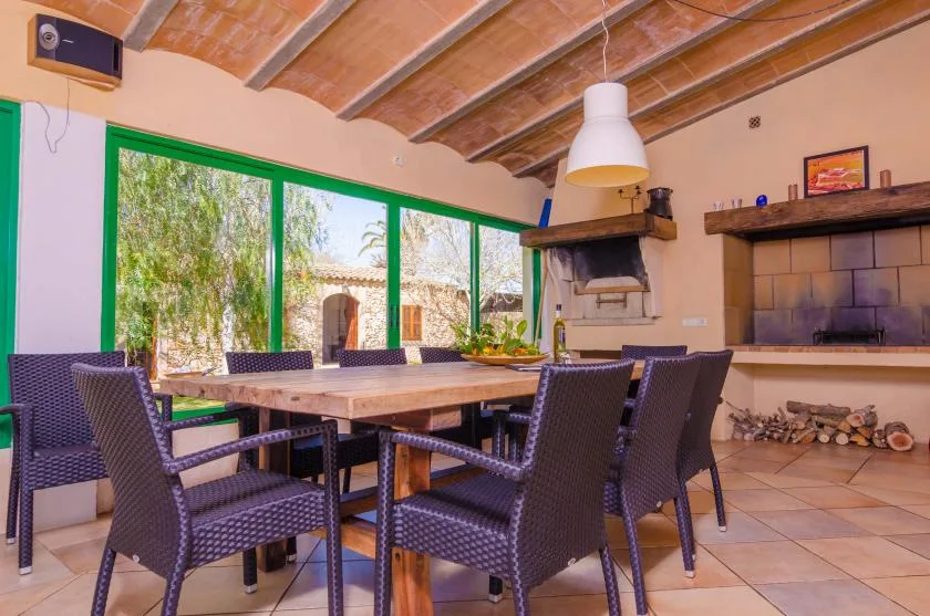 A dining area with a long table, woven seating, and a fireplace.
