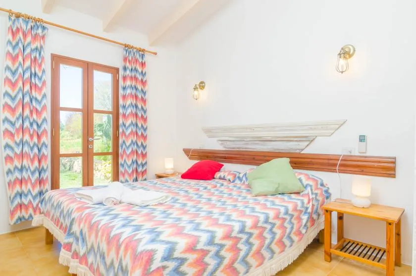 A bedroom with a colorful patterned bedspread and a glass-paneled door.