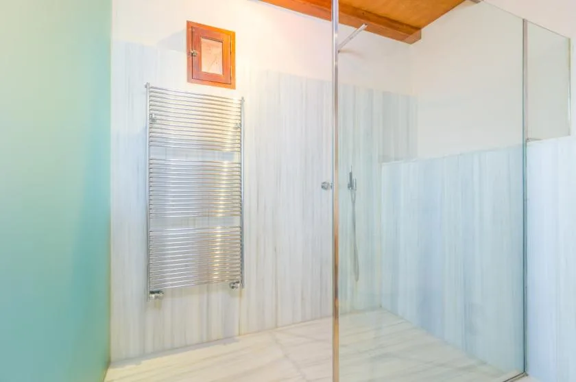 A bathroom with a glass shower and a wall-mounted towel warmer.