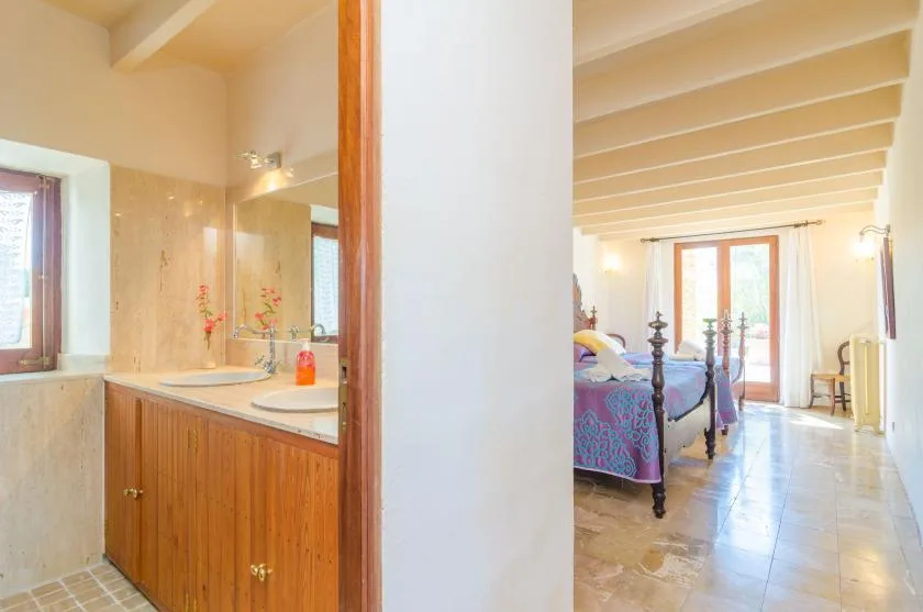 A bedroom with a tiled bathroom vanity visible through the doorway.