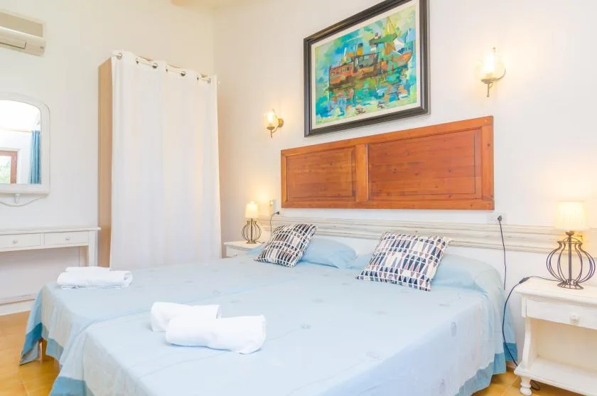 A bedroom with a large bed, blue bedding, and a framed painting above the headboard.