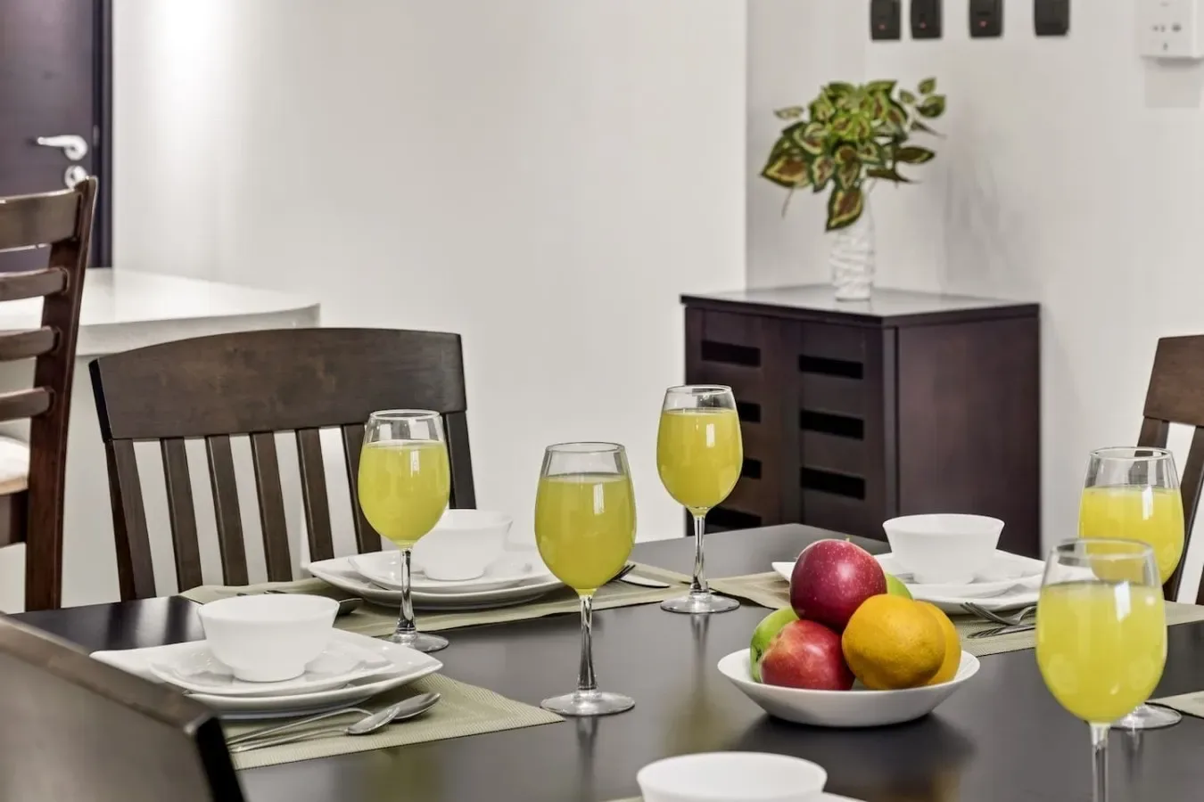 Comedor con una mesa puesta, fruta y vasos de jugo.