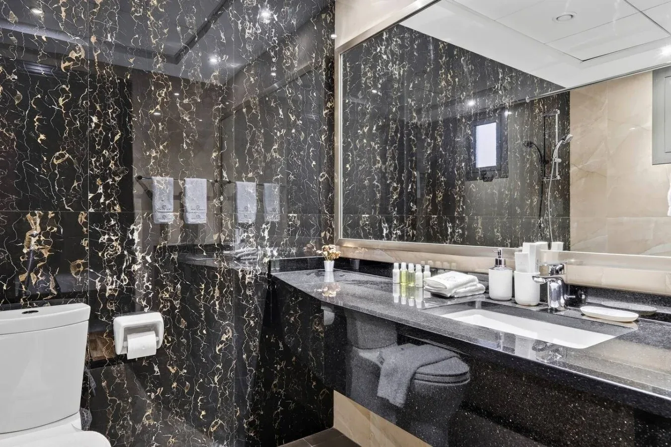 Un baño con lavabo y un espejo grande frente a paredes oscuras estampadas.