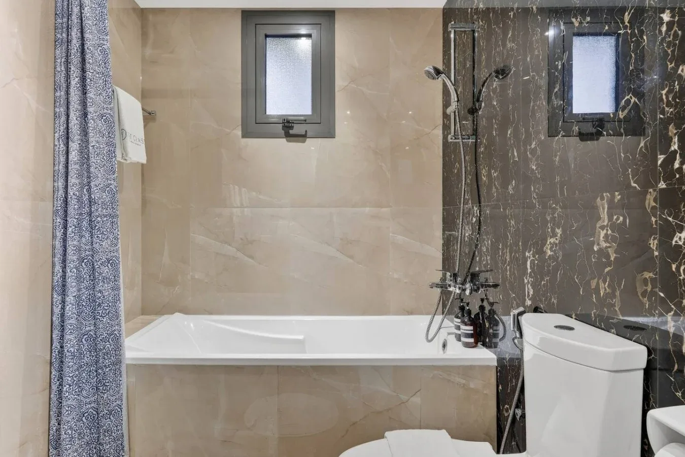 Baño con bañera, accesorios de ducha e inodoro.