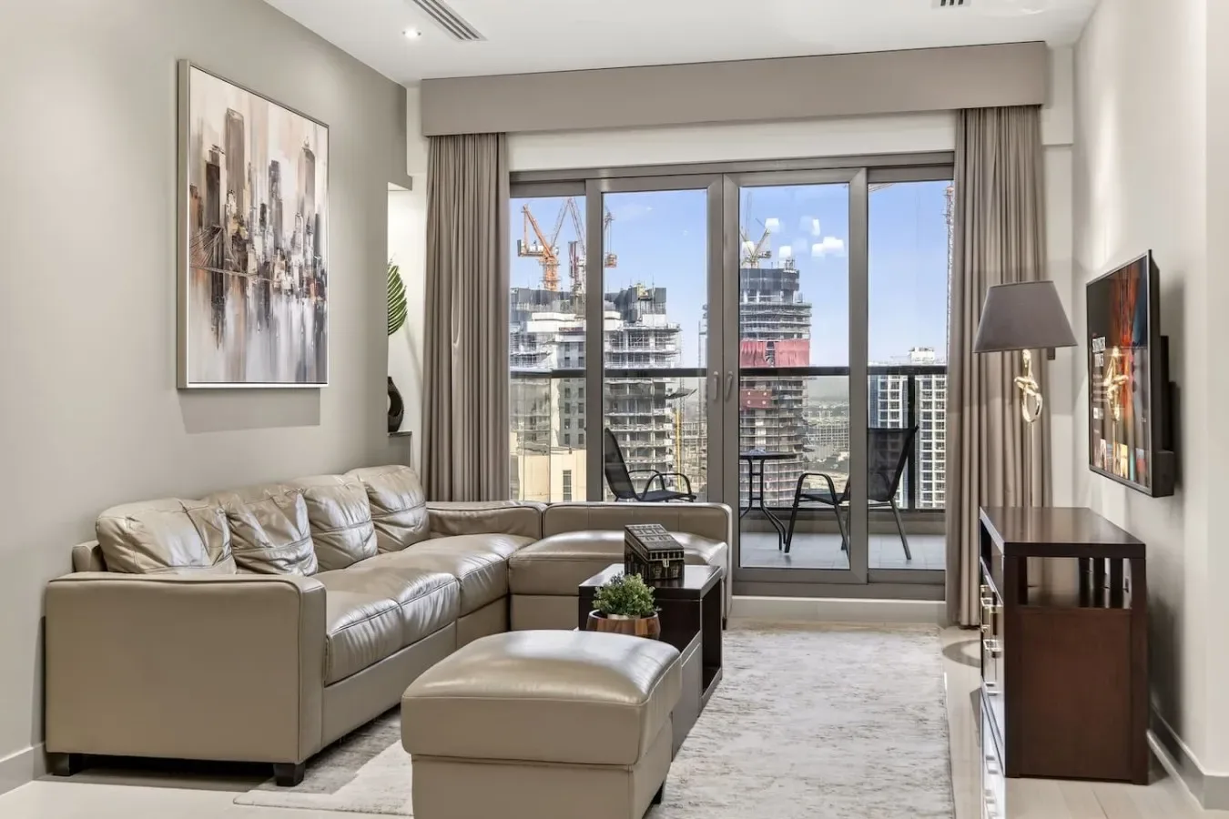 A living room with sectional seating and large windows overlooking nearby buildings.