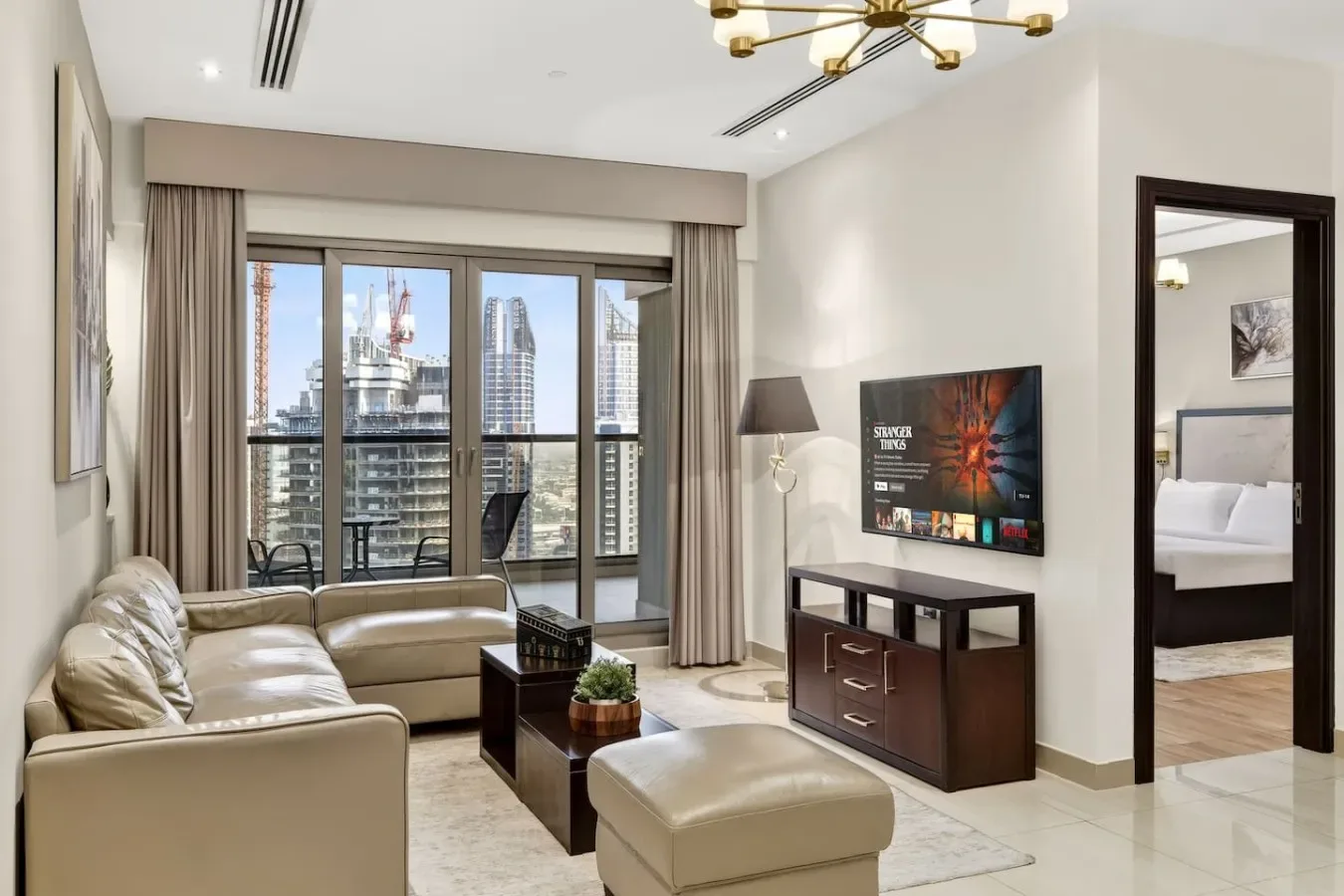 Una sala luminosa con asientos y un televisor junto a grandes ventanales.
