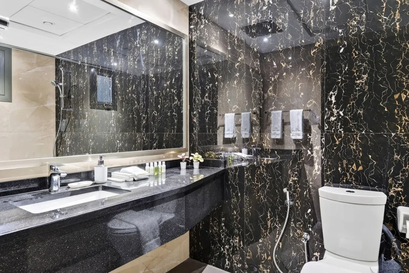 Un baño con un tocador largo, un espejo grande y un inodoro.