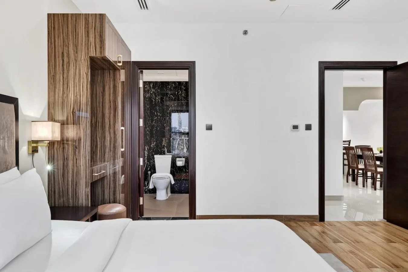 Dormitorio con una cama, un armario con acabado de madera y una puerta abierta al baño.