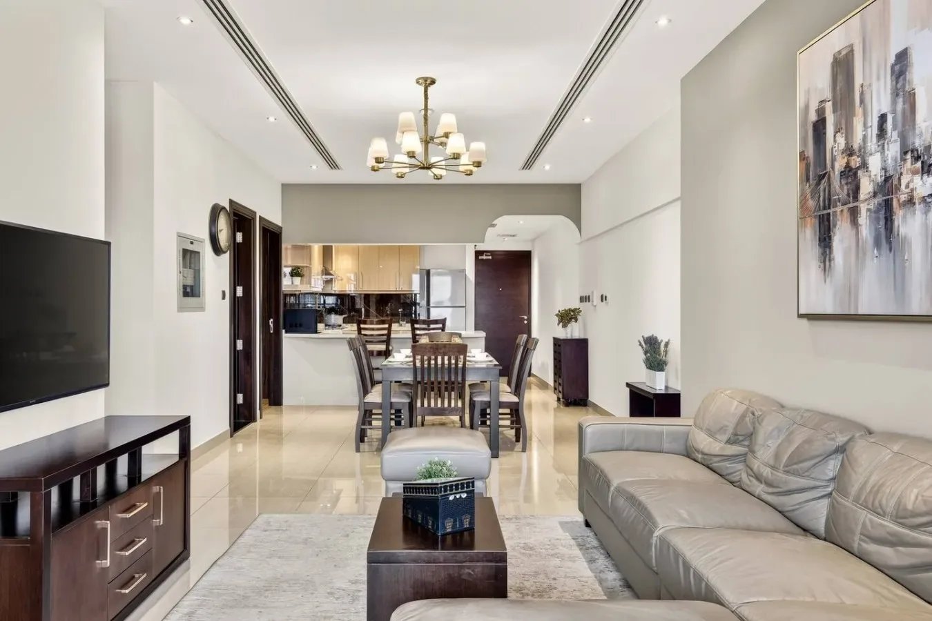 Una sala-comedor moderna con televisor, asientos y una cocina abierta.