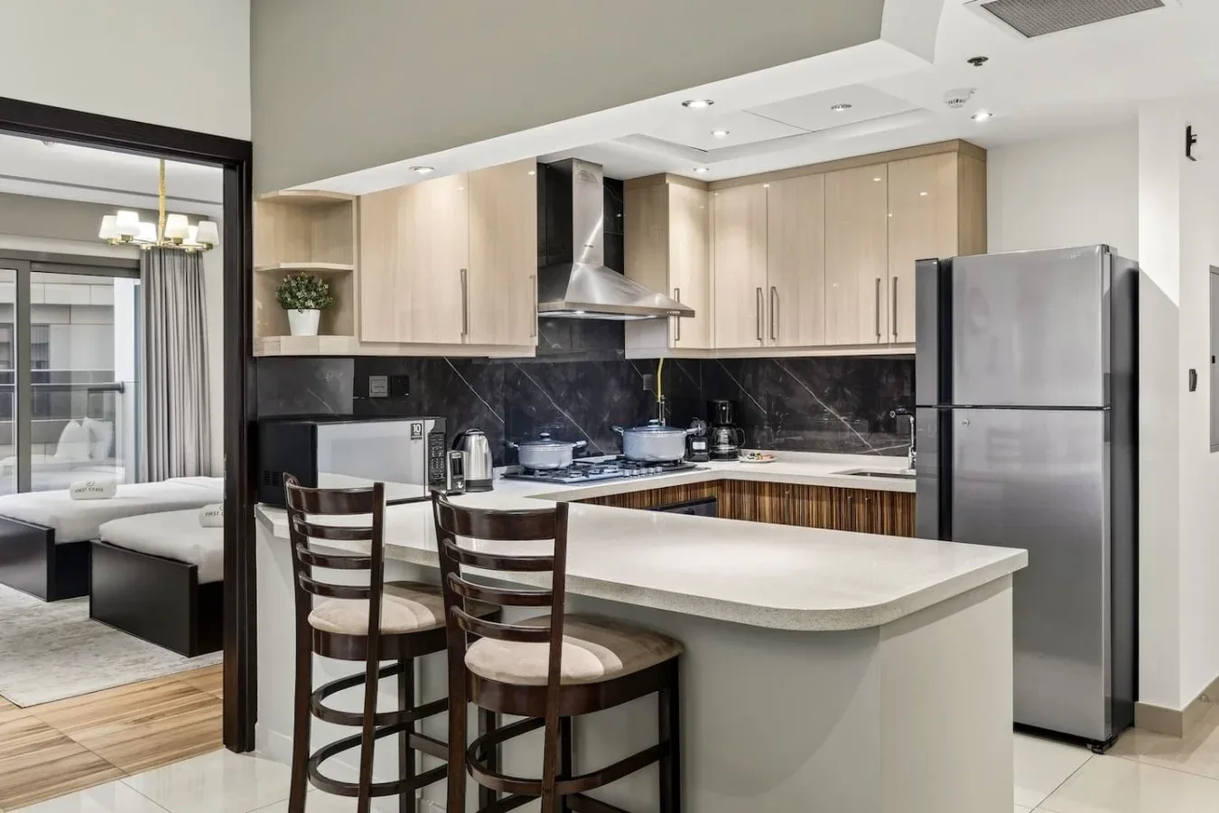 Cocina moderna con una isla central, asientos de barra y electrodomésticos de acero inoxidable.