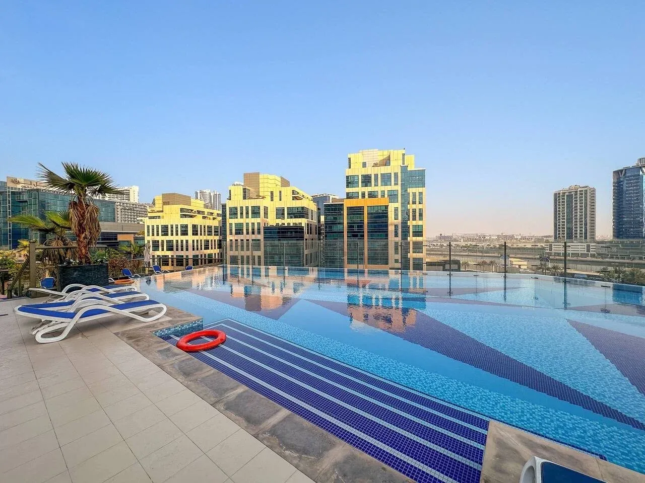 Una piscina en la azotea ofrece vistas de los edificios de la ciudad bajo un cielo despejado.