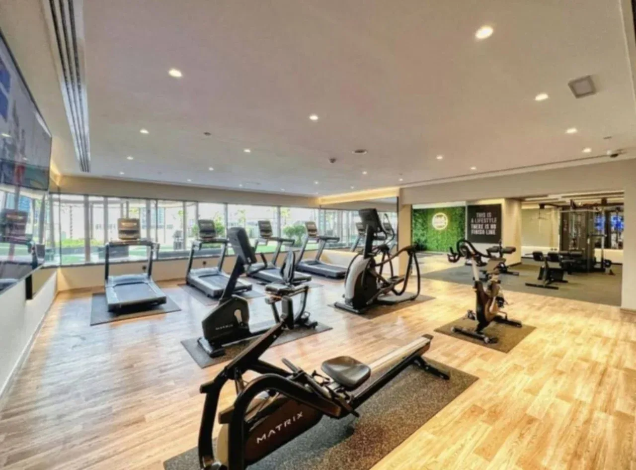 Sala de ejercicio con máquinas y ventanales.