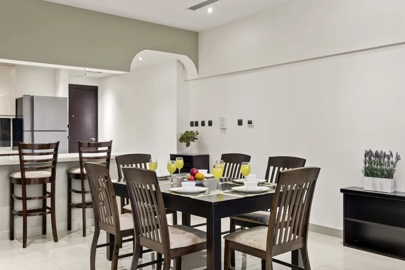 A dining area with a dark table and chairs beside an open kitchen.