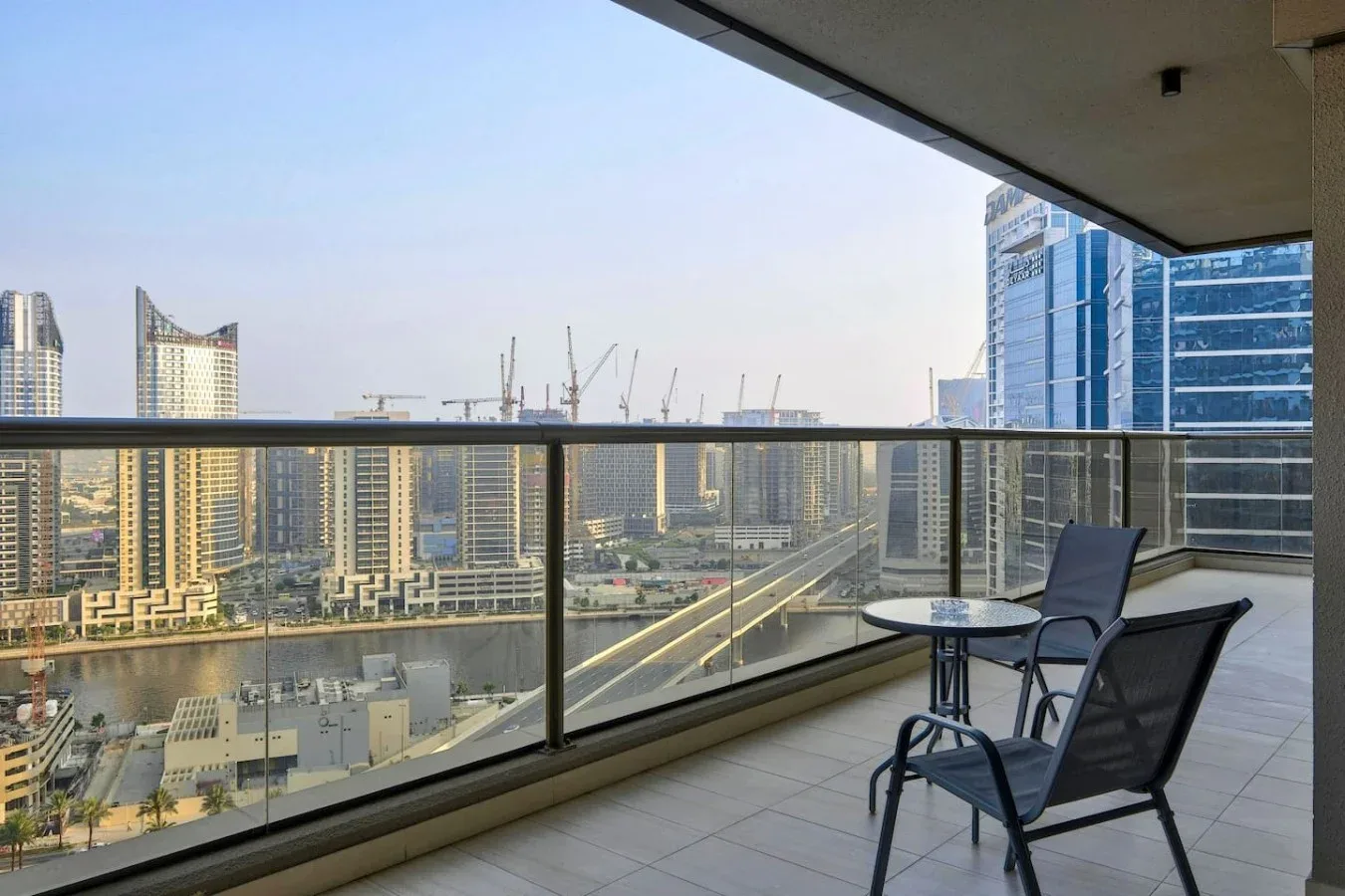 Un balcón con asientos ofrece vistas de edificios y grúas de construcción.