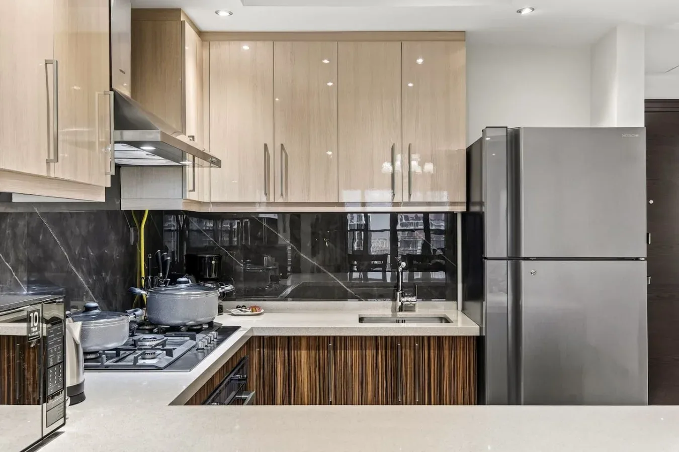 Una cocina moderna con gabinetes de madera clara y encimeras oscuras.