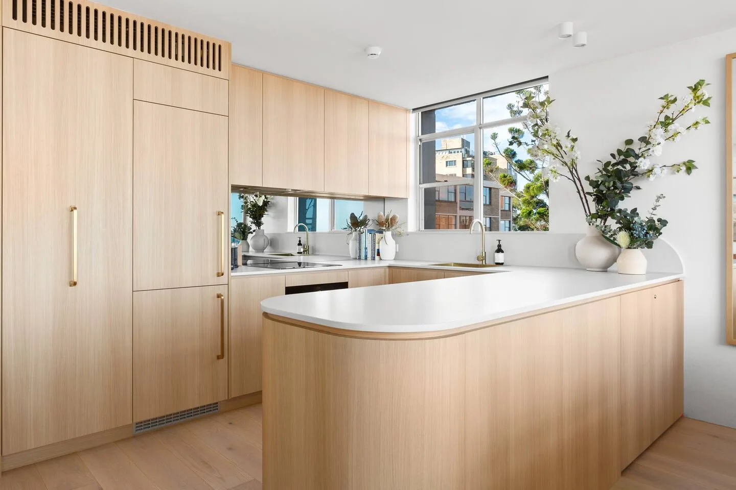 A bright kitchen with light wood cabinetry and a broad island.