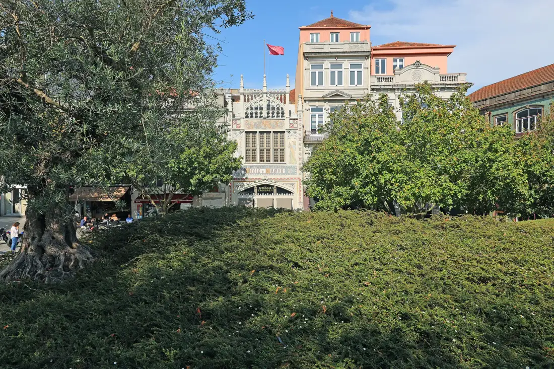 A leafy garden with trees in front of a large historic-looking building.