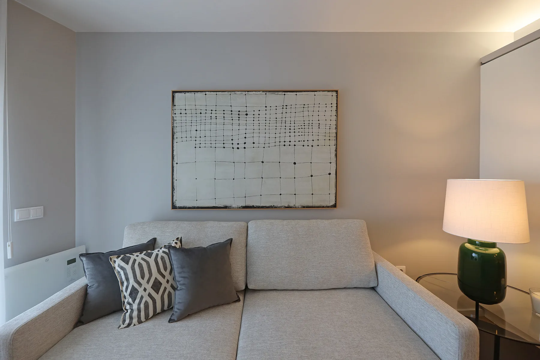 A living room with a light-colored sofa and a framed abstract artwork.