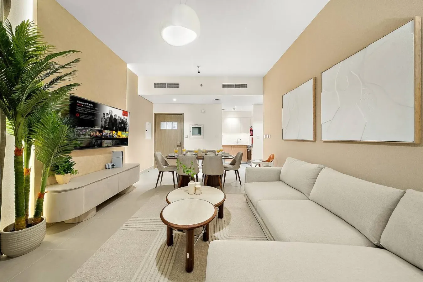 Una luminosa sala de estar con un sofá grande, comedor y una palmera en maceta.