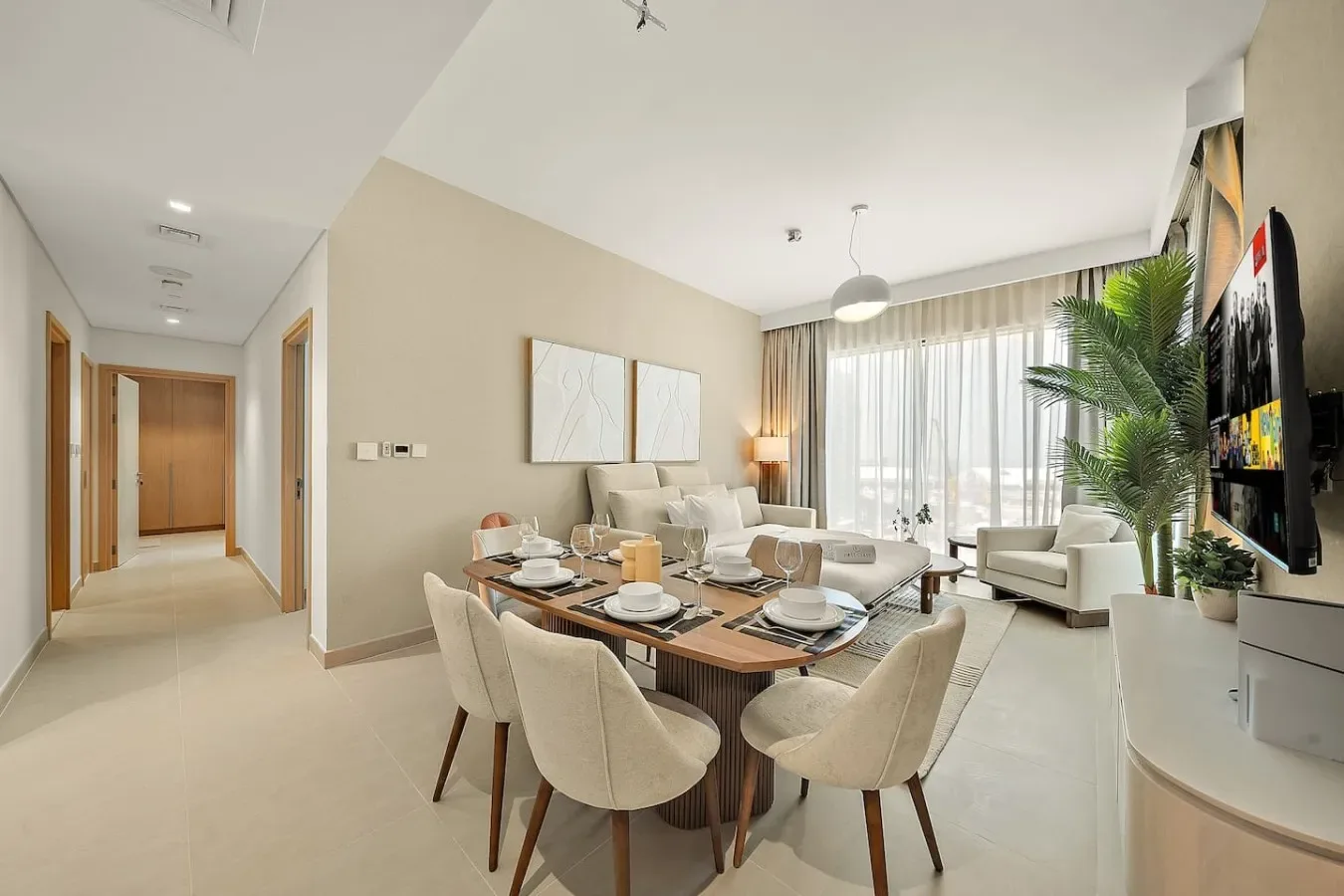 A bright dining and living area with a table set beside large windows.