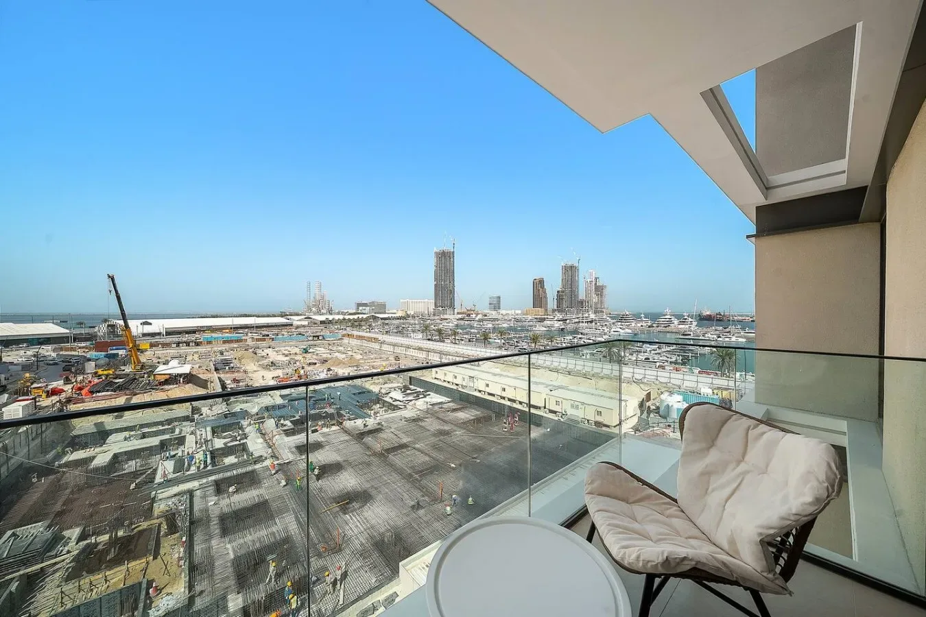 A balcony seating area overlooks a construction site and distant city buildings.
