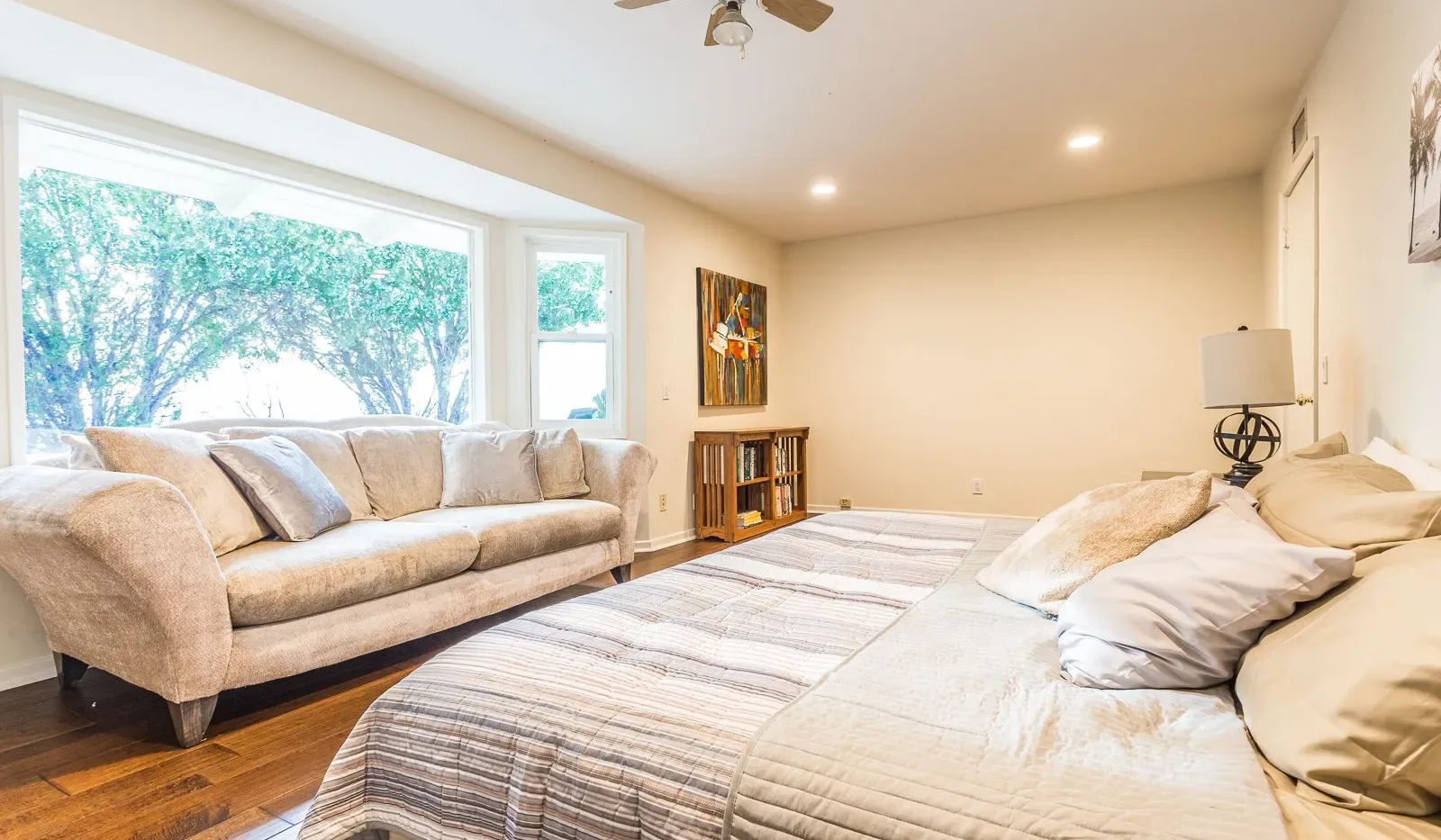Un dormitorio luminoso con una cama grande, un sofá y ventanas amplias.