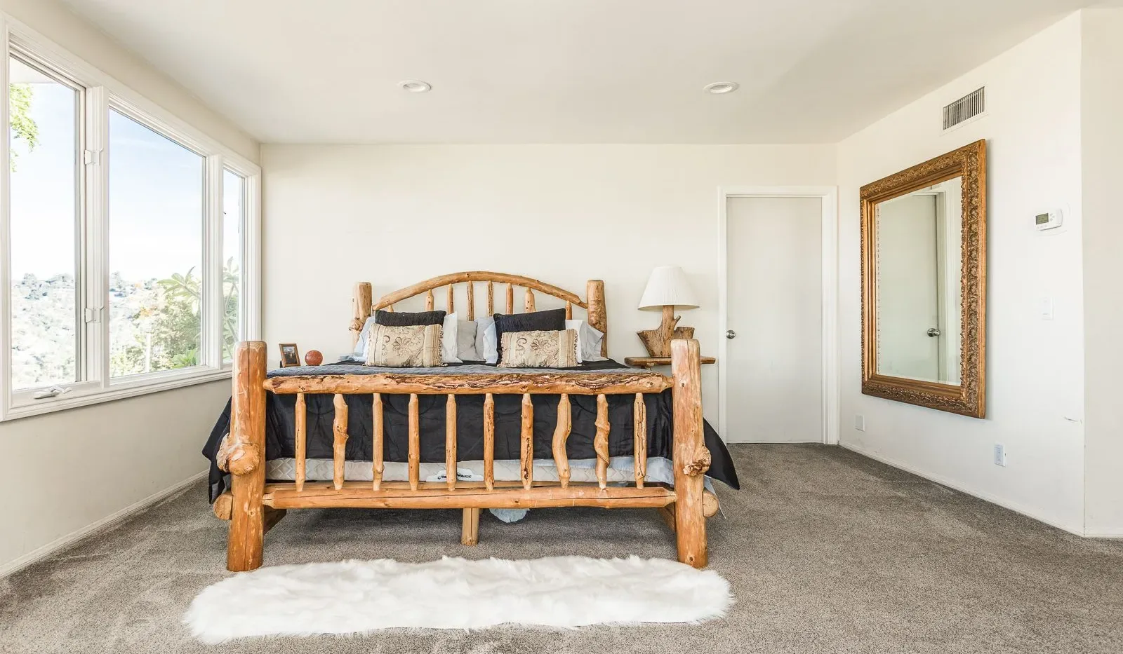 Un dormitorio con una cama de madera y ventanas grandes.
