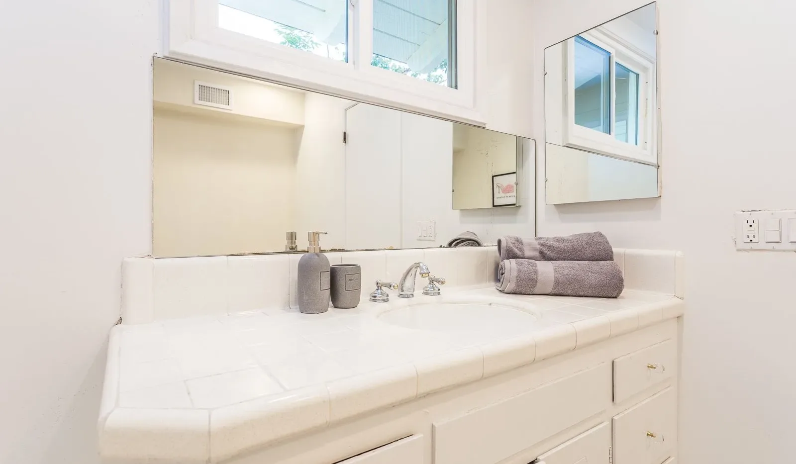 Un tocador de baño luminoso con una encimera amplia, lavabo y espejo.