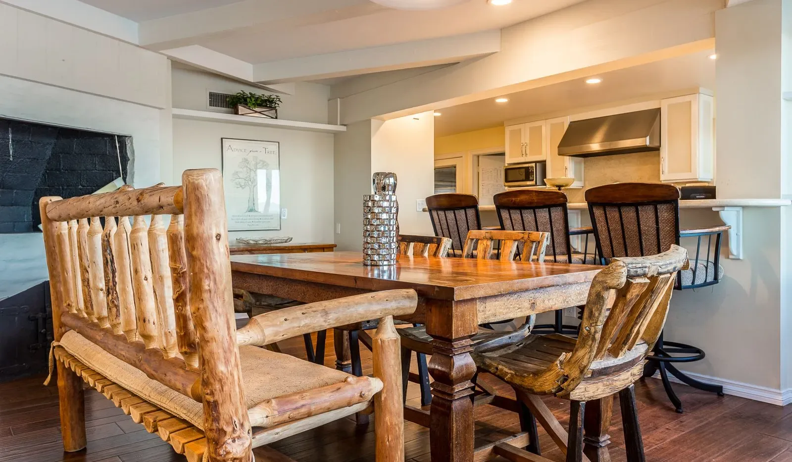 Comedor con una mesa y sillas de madera rústica, abierto a la cocina.