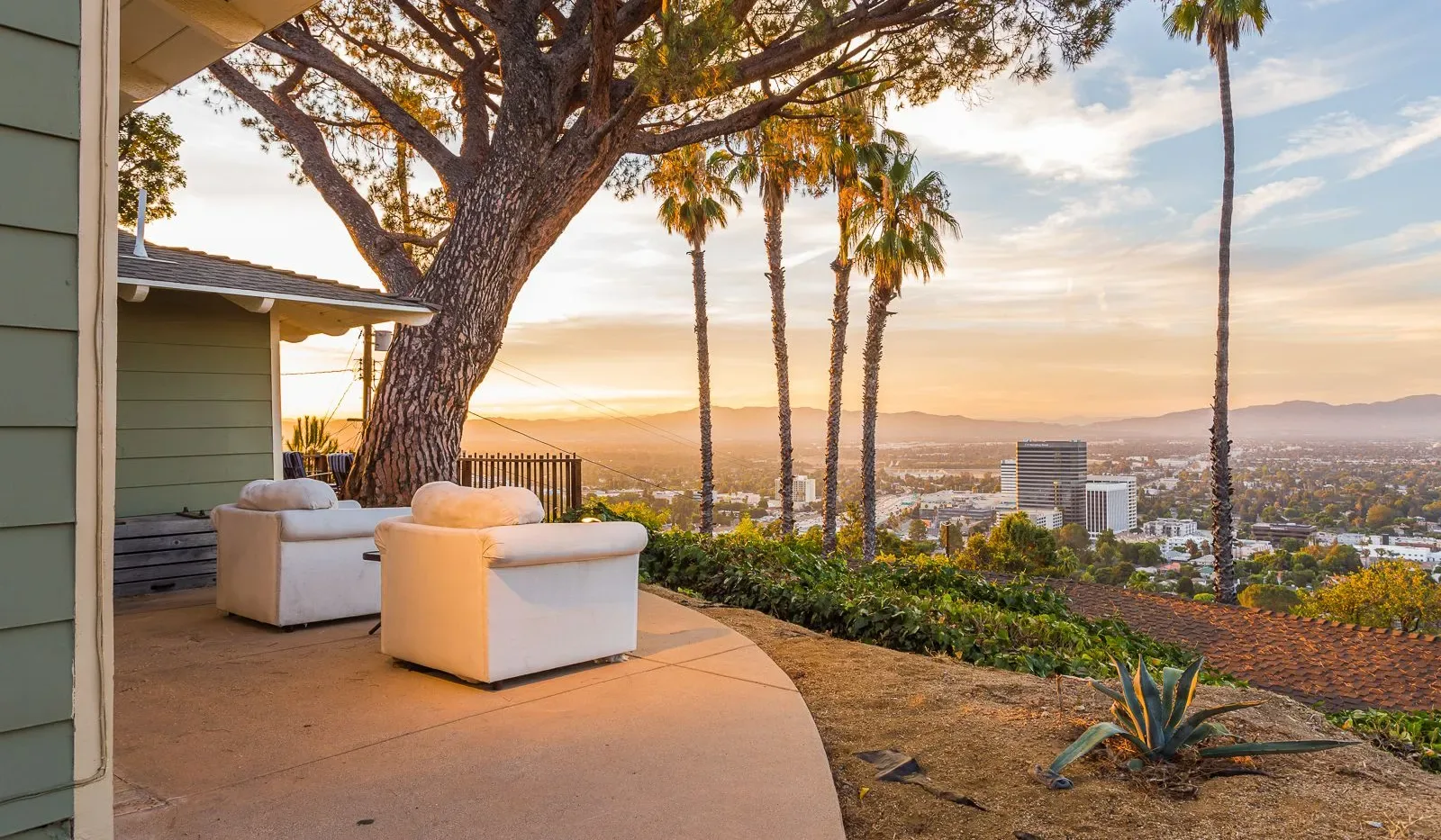 Un patio al aire libre con asientos ofrece vistas de una ciudad al atardecer.