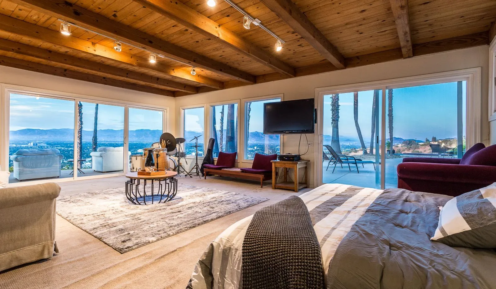 Un dormitorio da a una sala de estar acristalada con vistas al agua.