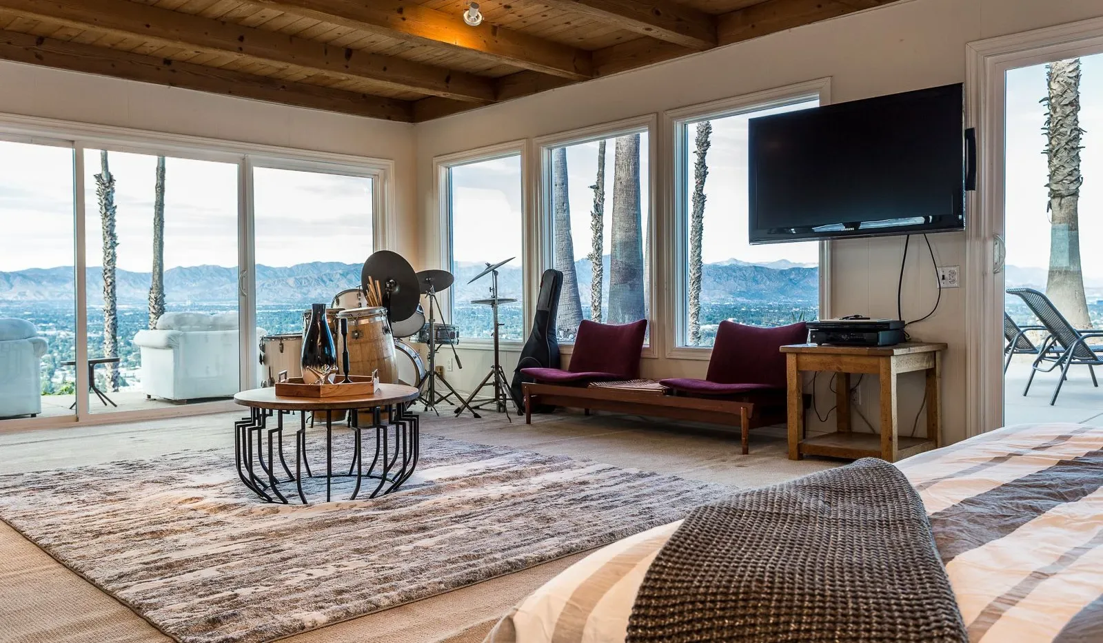 Una sala de estar con asientos, un televisor y grandes ventanas con vistas al agua.