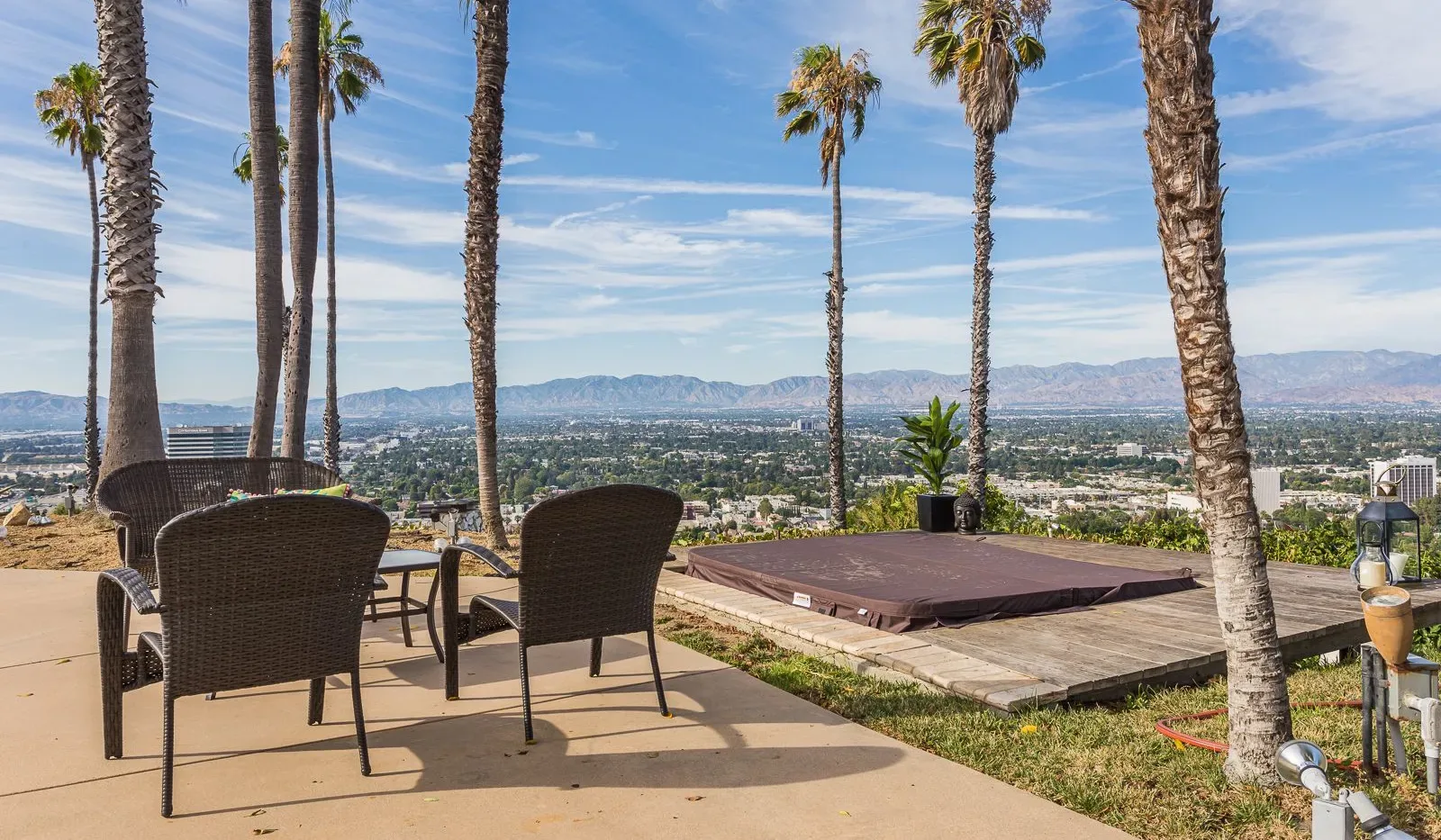 Un patio al aire libre con asientos y una plataforma baja rectangular, con vistas a la ciudad y las montañas.