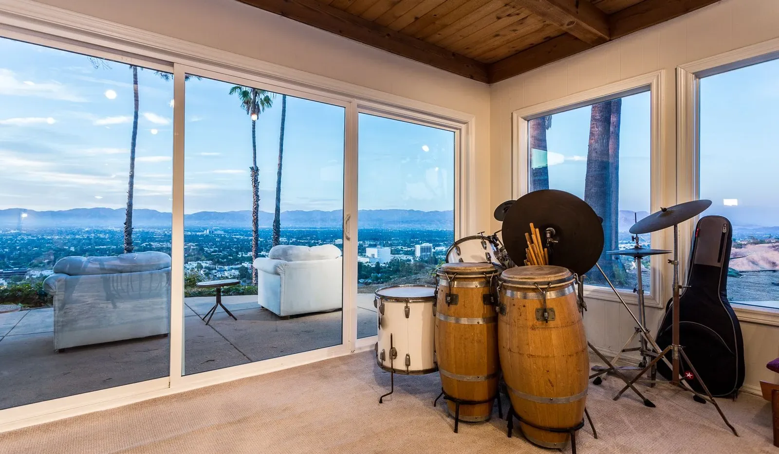 Una sala de música con tambores y vistas de la ciudad por grandes ventanales.