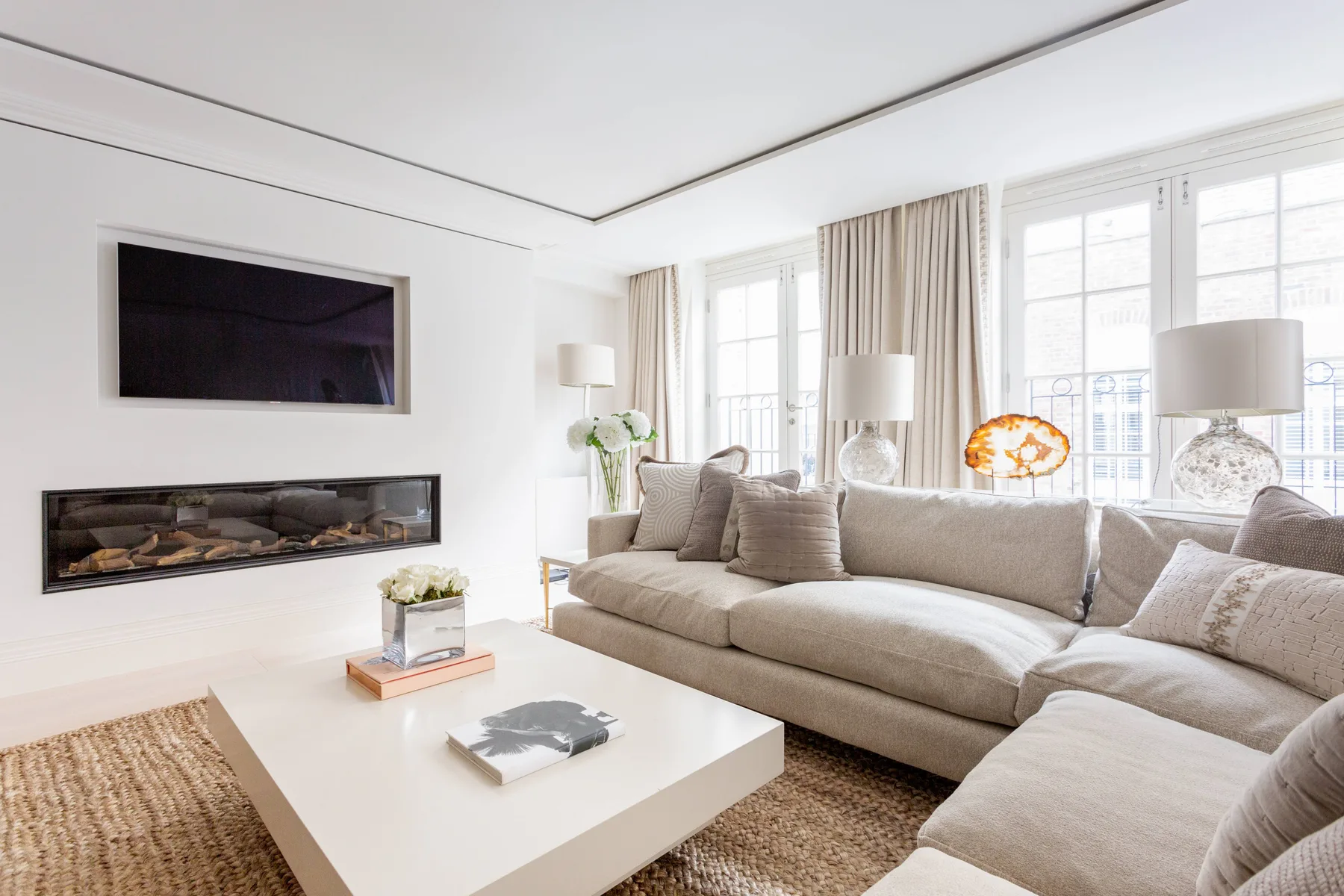 A bright living room with a sectional sofa, coffee table, and large windows.