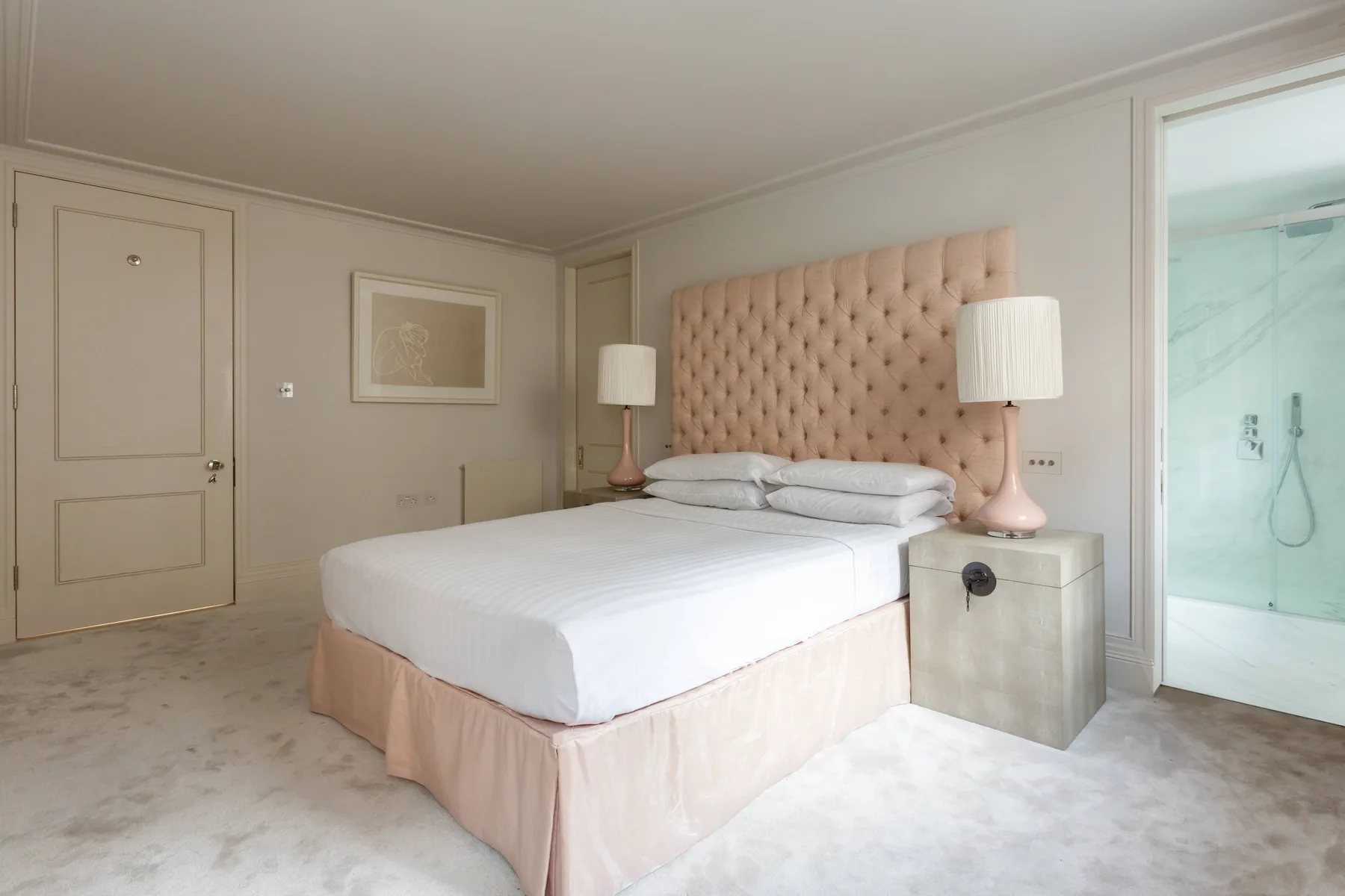 A bedroom with a neatly made bed and a glass-enclosed shower area.