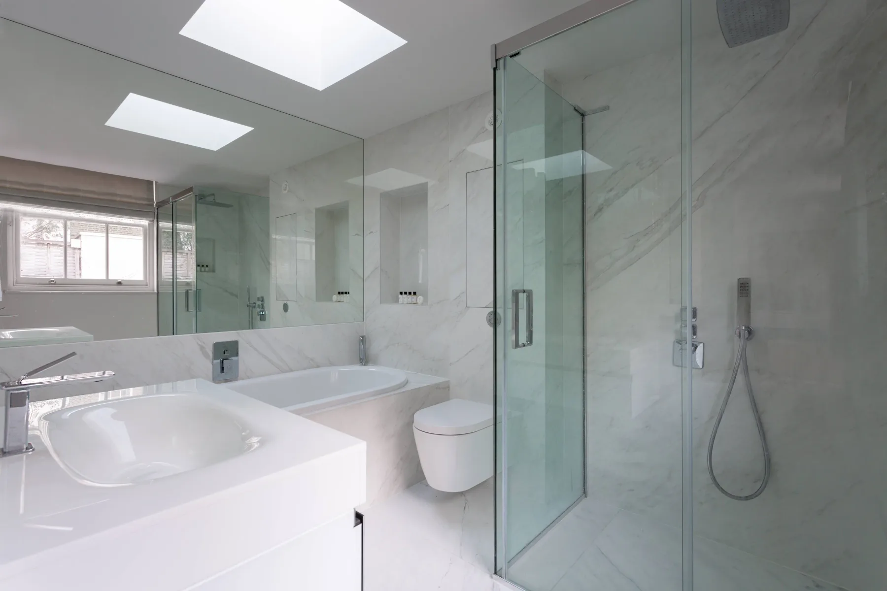 A bright bathroom with a bathtub, sink, and glass shower.