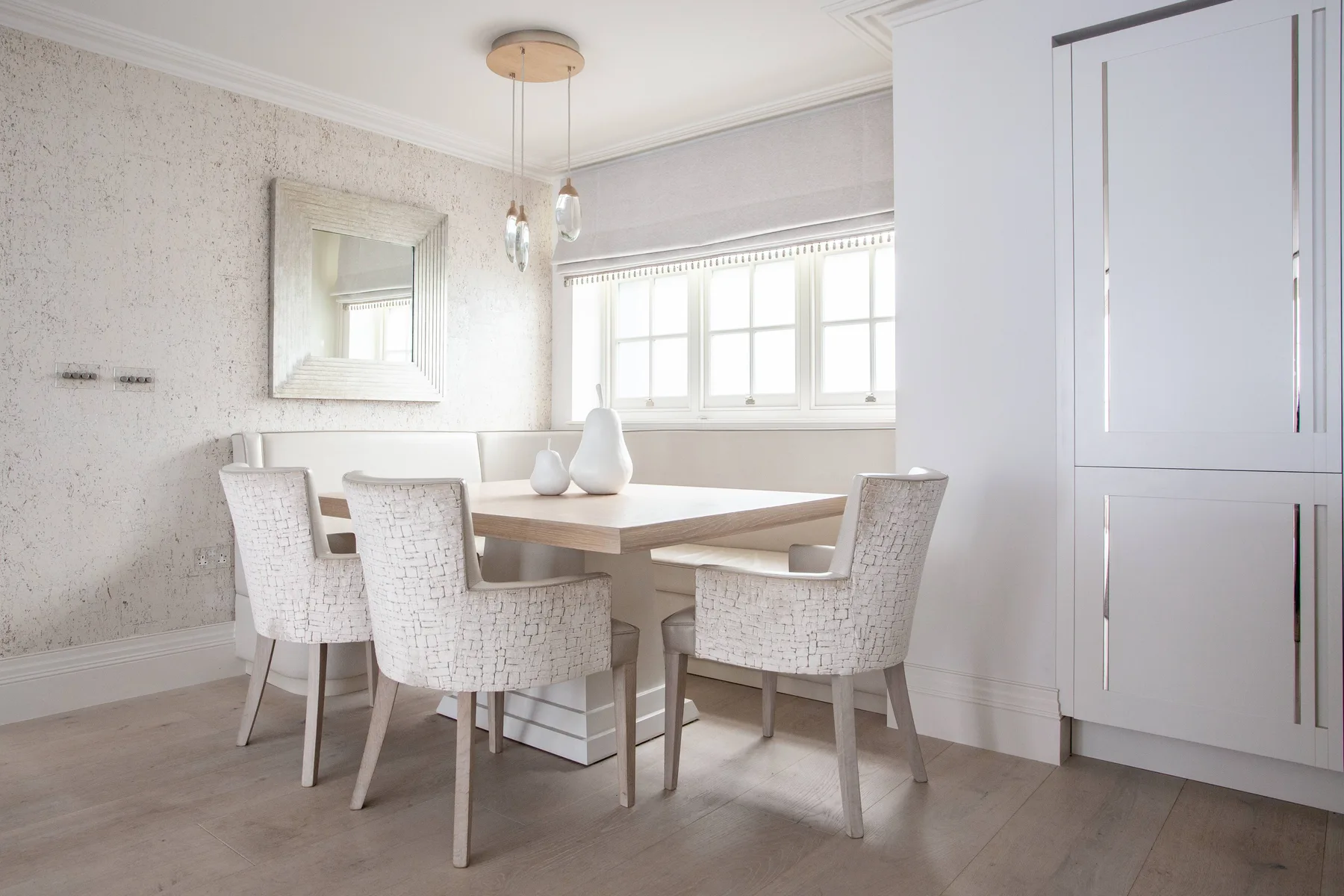 Un comedor luminoso con una mesa, sillas y una hilera de ventanas.