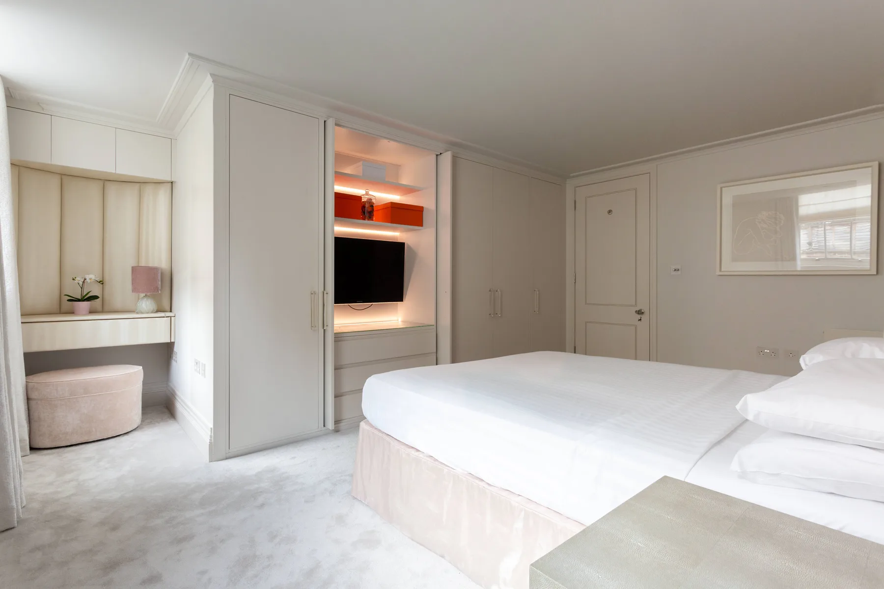 A bright bedroom with a large bed and a television set into the wall.