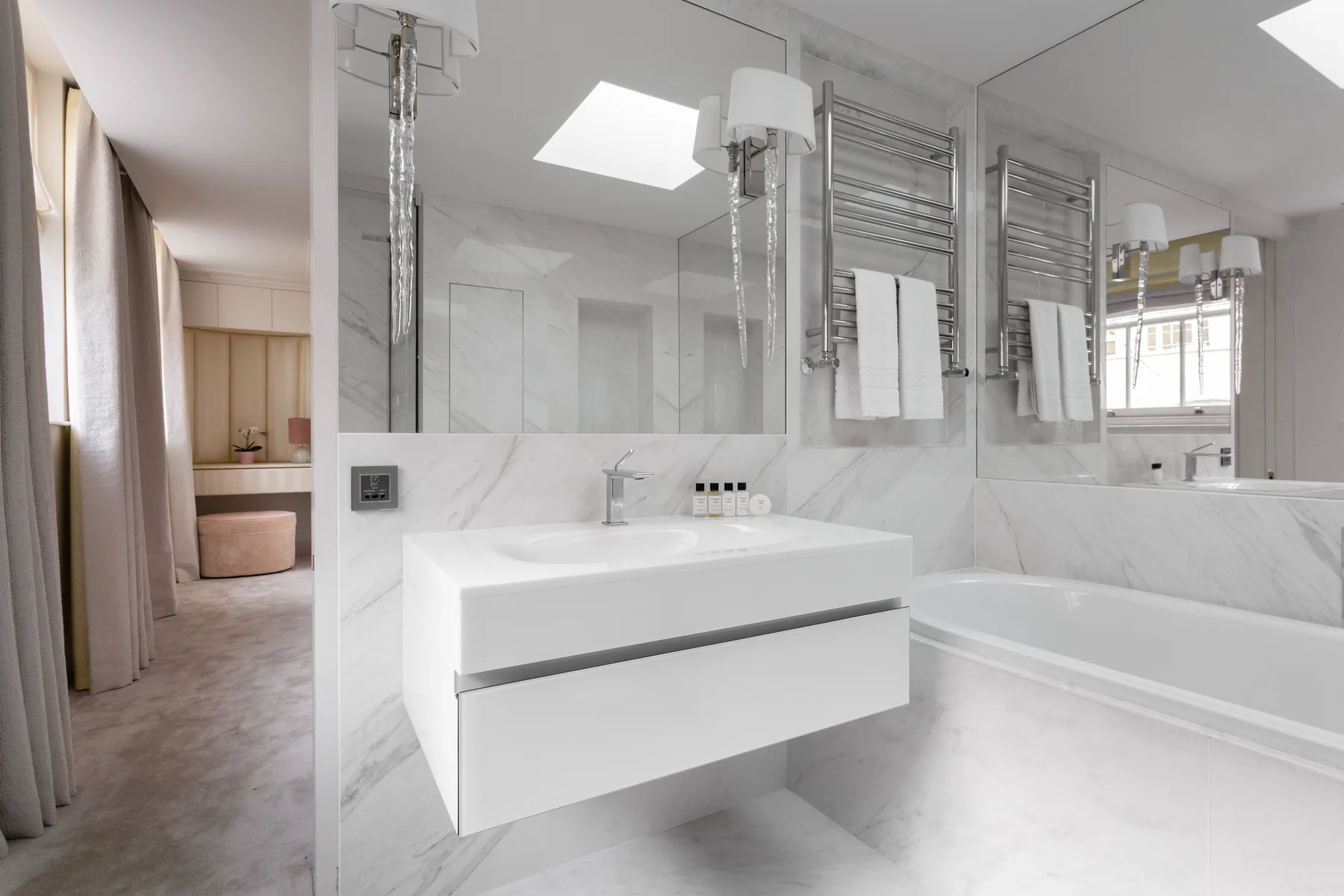 A bright bathroom with a floating vanity and a bathtub beside the wall.