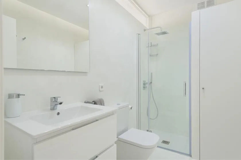 A bright bathroom with a white sink vanity and glass shower.